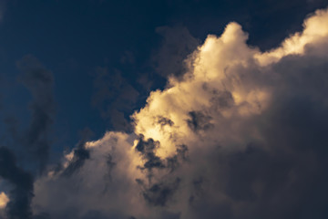 gray Cumulus clouds in a blue sky with orange light