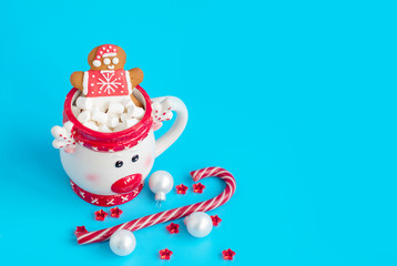 Christmas Cup of hot chocolate with marshmallow and gingerbread man on a blue background. Creative concept of New year and Christmas