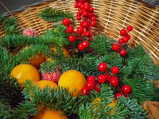 Christmas composition of  tangerines, fir branches,  red berries and balls in a basket. Christmas and New Year background