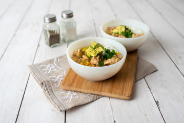 Flavorful White Chicken Chili made with hearty beans, tender chicken, and a rich and creamy broth in slow cooker, garnished with sour cream and avacado