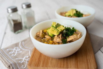 Flavorful White Chicken Chili made with hearty beans, tender chicken, and a rich and creamy broth in slow cooker, garnished with sour cream and avacado