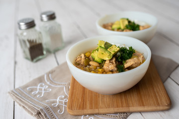 Flavorful White Chicken Chili made with hearty beans, tender chicken, and a rich and creamy broth in slow cooker, garnished with sour cream and avacado