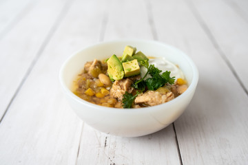 Flavorful White Chicken Chili made with hearty beans, tender chicken, and a rich and creamy broth in slow cooker, garnished with sour cream and avacado