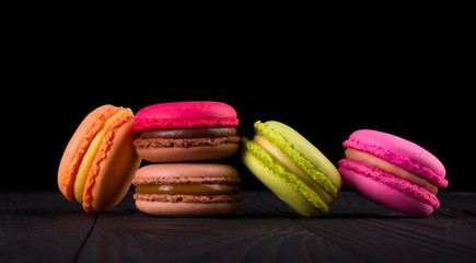 Heap of french colorful macaroons on wooden table isolated on black