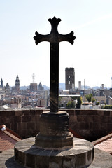 Silhouette of Cross against Hazy Vista of Spanish City Rooftops 