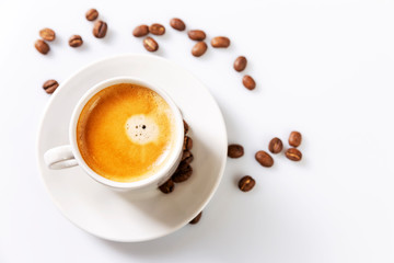 A small white cup of coffee stands on coffee beans. Fragrant pleasure. Space for text. White background.