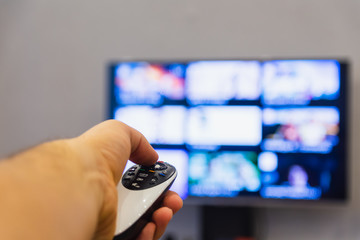 A man holds in his hand TV remote control. The man switches channels, choosing what to watch. Recreation and entertainment concept. Leasure and lifestyle.