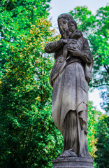 Fototapeta premium Stone statue of Virgin Mary with a child in the park.