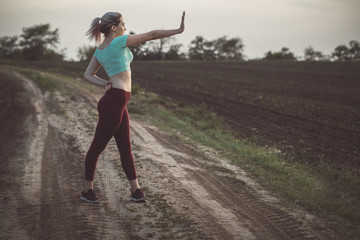 slim young woman in sportswear exercises and stretches hands in the field, girl engaged in sport outdoors on nature, concept healthy lifestyle and female beauty