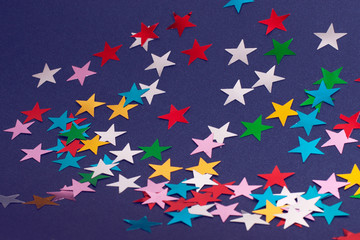 Fototapeta premium Festive colorful stars background. Christmas abstract flat-lay.