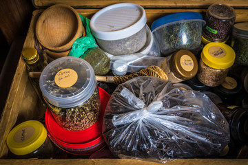 open, old travel suitcase with a broken handle, different dishes with dried flowers, herbs, leaves - all for the sauna bath procedures