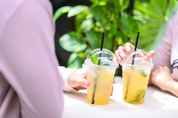 Cropped image of young couple in love drinking soft-drink in cafe
