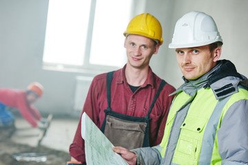 foreman builder and construction worker with blueprint in indoor apartment
