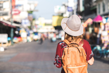 Travel Thailand concept. Young woman with hat traveling in walking street Khaosan road  in Bangkok, Thailand
