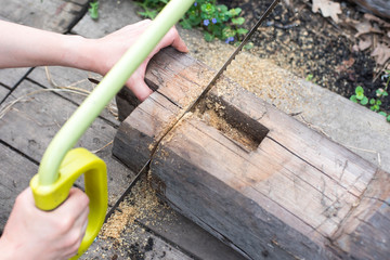 man sawing a tree with a hand saw.