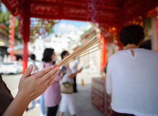 Close-up of a woman holding a hand with an incense burning to pay respect to god according to Asian beliefs. For the new year to come, only good things come to life.