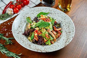 Tasty eel salad in teriyaki sauce with spinach, chili pepper and lettuce in a white bowl on a wooden background. Seafood salad. Delicious and healthy food. Close up