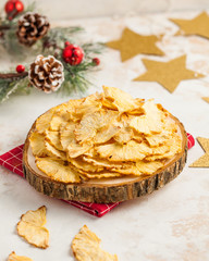 Lots of dried pineapples, pineapple chips on a wooden plate. Christmas background with gold stars and Christmas tree wreath. New year's vegetarian snack.