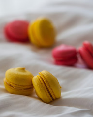 Colorful macaroon cakes on white background. Yellow and red macaroons on white bedding.