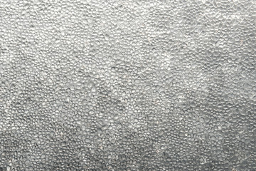 Frozen water drops on a window. It rained when the temperature was low, and the rain froze when it struck the window. 