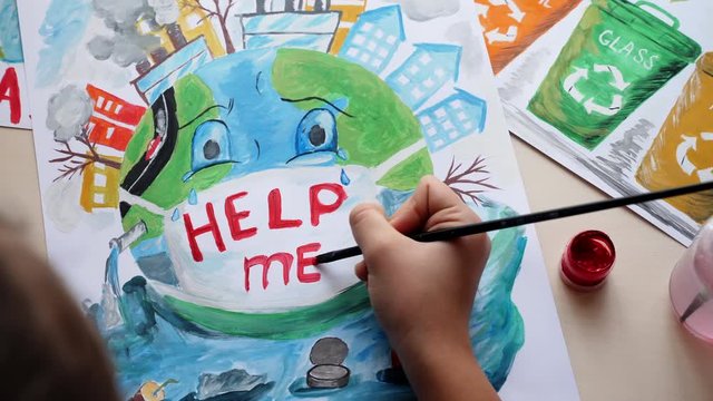 Concept save our planet. Top view of a young girl paints posters calling to save planet Earth from pollution