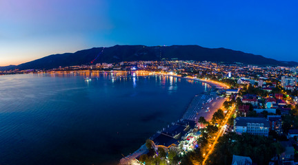 Evening panorama of the seaside resort of Gelendzhik. the sun went down, dark blue sky and sea. Visible Bay, beach and promenade in the lights. The city is beautifully lit. 
