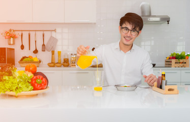 Asian handsome businessman pouring orange juice into the glass