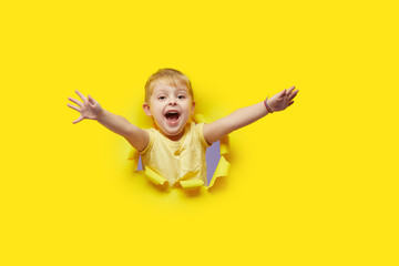 Little child looking, peeping through the bright yellow paper hole. Advertise children's goods. Wow...