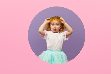 Surprised Little Child girl in heart shap sunglasses looking out of a pink round hole. Banner. Happy girl Looking at camera. Wow funny face