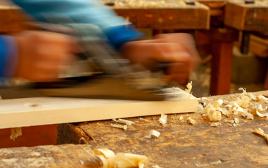 profession, people, carpentry, woodwork and people concept - carpenter working with jointer planing wood plank at workshop