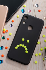 Black phone case decorated with yellow sad smile