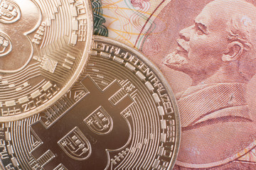 Two Bitcoin coins lie on top of Soviet paper money rubles with the symbol of the USSR Lenin.