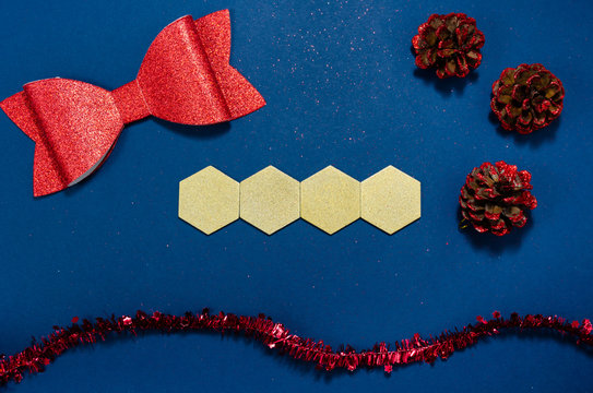 Gold wooden hexagons with copy space and red bow, cones and girland in a  conceptual image of the coming new year. Over blue background.