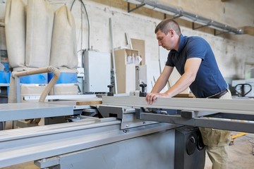 Male carpenter using machine in woodworking woodshop