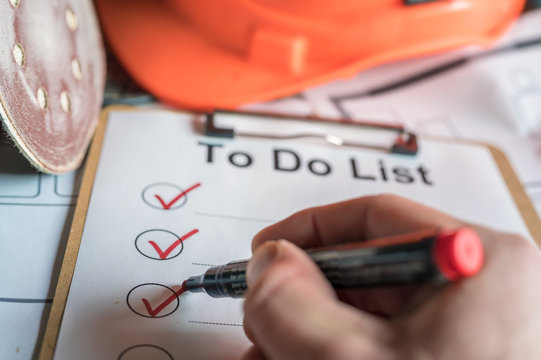 Abhaken einer To do Liste auf einer Baustelle als Symbol f&uuml;r organisiertes Arbeiten