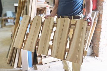 Male carpenter showing new made wooden low fence in carpentry