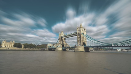 Tower Bridge London Time lapse. Famous monument standing on Thames river in England. Tourist boats sailing along the coast. Soft clouds fast flow in blue sky. Travel recreation concept.