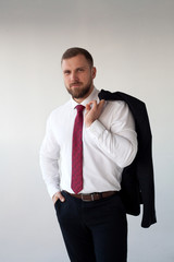 Male model in white shirt and red tie, black jacket and trousers, athletic build, isolated on a white background. The concept of classic clothes or office style.