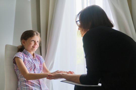 Woman Social Worker Psychologist Talking To Girl Child In Office