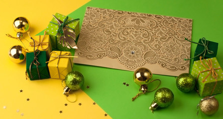 Christmas  graphic multi-colored background from yellow, green and blue paper with a geometric pattern, with gifts and Christmas toys and a carved greeting card with a pattern