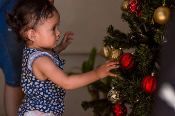 Child looks christmas spheres on a christmas tree