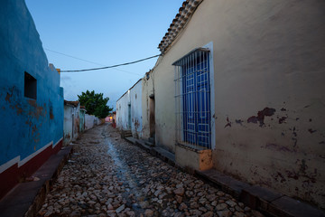 Fototapeta premium Trinidad, Cuba. Street view of a Residential neighborhood in a small Cuban Town during a cloudy and sunny sunrise.