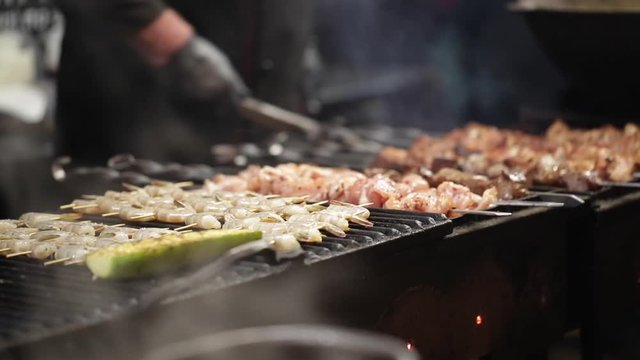 Fresh kebab meat roasted on fire . Selective focus. Meat on grill. Evening BBQ. Cooking barbecue on grill with smoke. Close-up meat spinning on skewer, cooked on coals in evening at food market