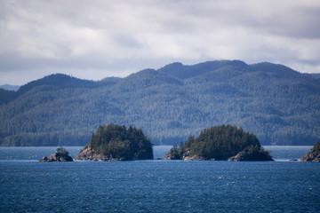 Fototapeta na wymiar Northern Vancouver Island, British Columbia, Canada. Rocky Islands on the Pacific Ocean during a sunny and cloudy day with Islands and the Mainland in the background.