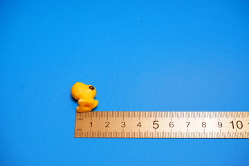 small toy dinosaur and a ruler on a blue background