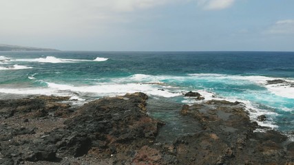 Flight over the unusual coast of the Atlantic Ocean, turquoise waves and a hard-to-reach beach. Aerial view of Tenerife, Spain