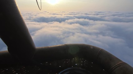 Adventure first person view, pov from basket of field, meadow, river and above cloud in flight on hot air balloon. The aircraft fly in morning blue sky. Hot air balloon burner flame into envelope.
