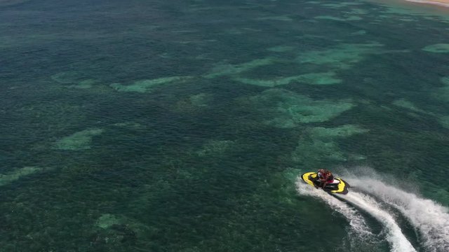 Aerial top view of jet ski racing on a crystal clear water. Extreme enjoying summer vacation. People are playing a water scooter in open sea waters. Watercraft adventure fresh day in summer holiday.