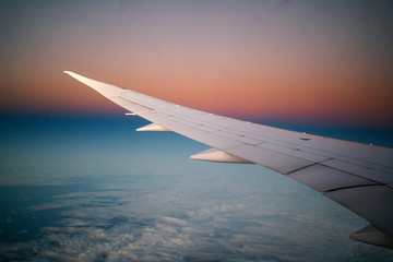 Wing of an airplane seen from the window during the flight at sunrise