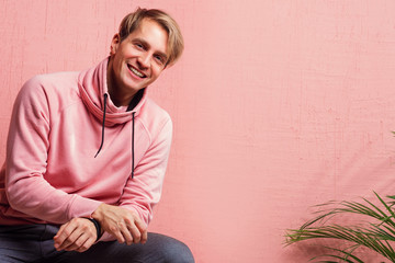 Happy and smiling young man in casual clothes looks at the camera, portrait with real emotions